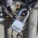 Detailed view of a padlock securing a metal gate with a chain, emphasizing safety and security.