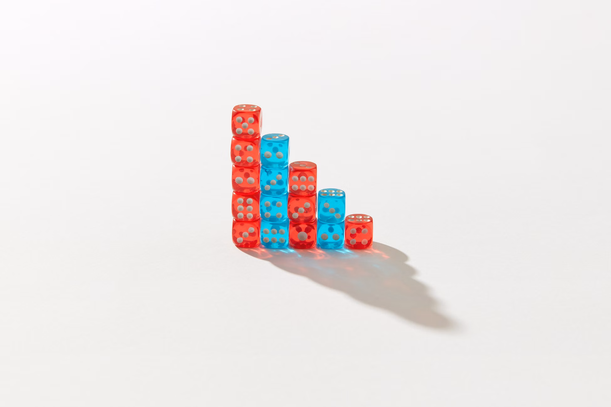 A creative arrangement of red and blue dice stacked in a descending pattern casting a shadow.