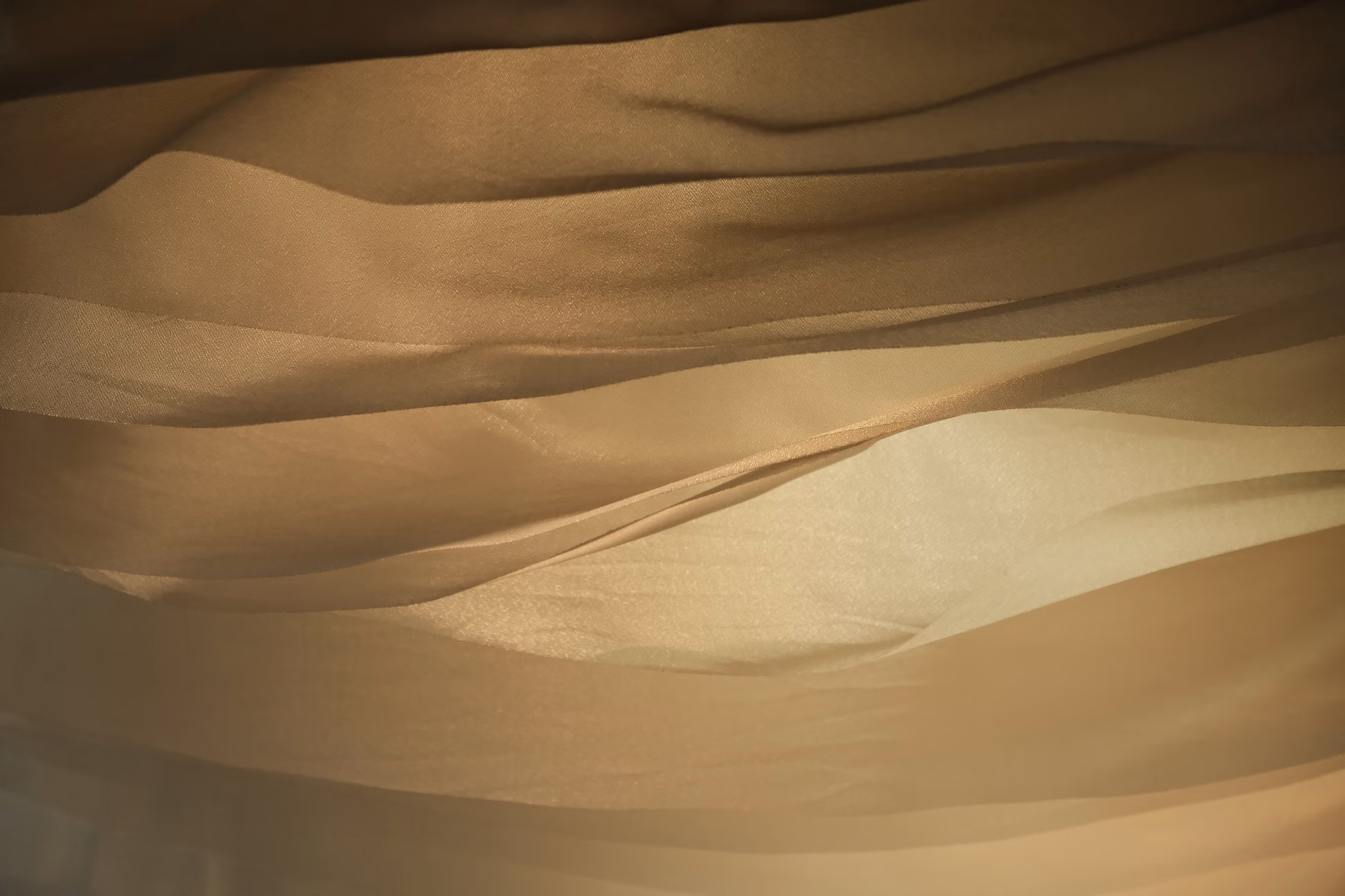 Soft, golden fabric waves create an abstract and calming visual pattern.