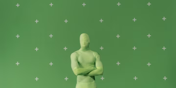 Person in a green chroma key suit standing against a marked green screen in a studio.