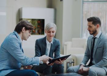 Three professionals engaging in a business meeting in a modern office setting.
