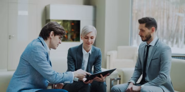 Three professionals engaging in a business meeting in a modern office setting.