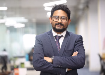 Confident man in a suit standing in a modern office, showcasing professionalism.