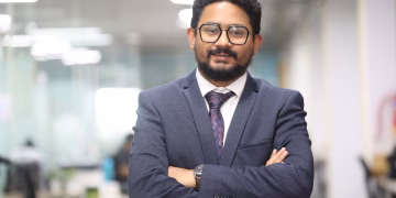 Confident man in a suit standing in a modern office, showcasing professionalism.