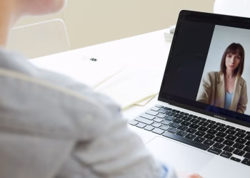 Close-up of woman on a video call using a laptop in a modern workspace.