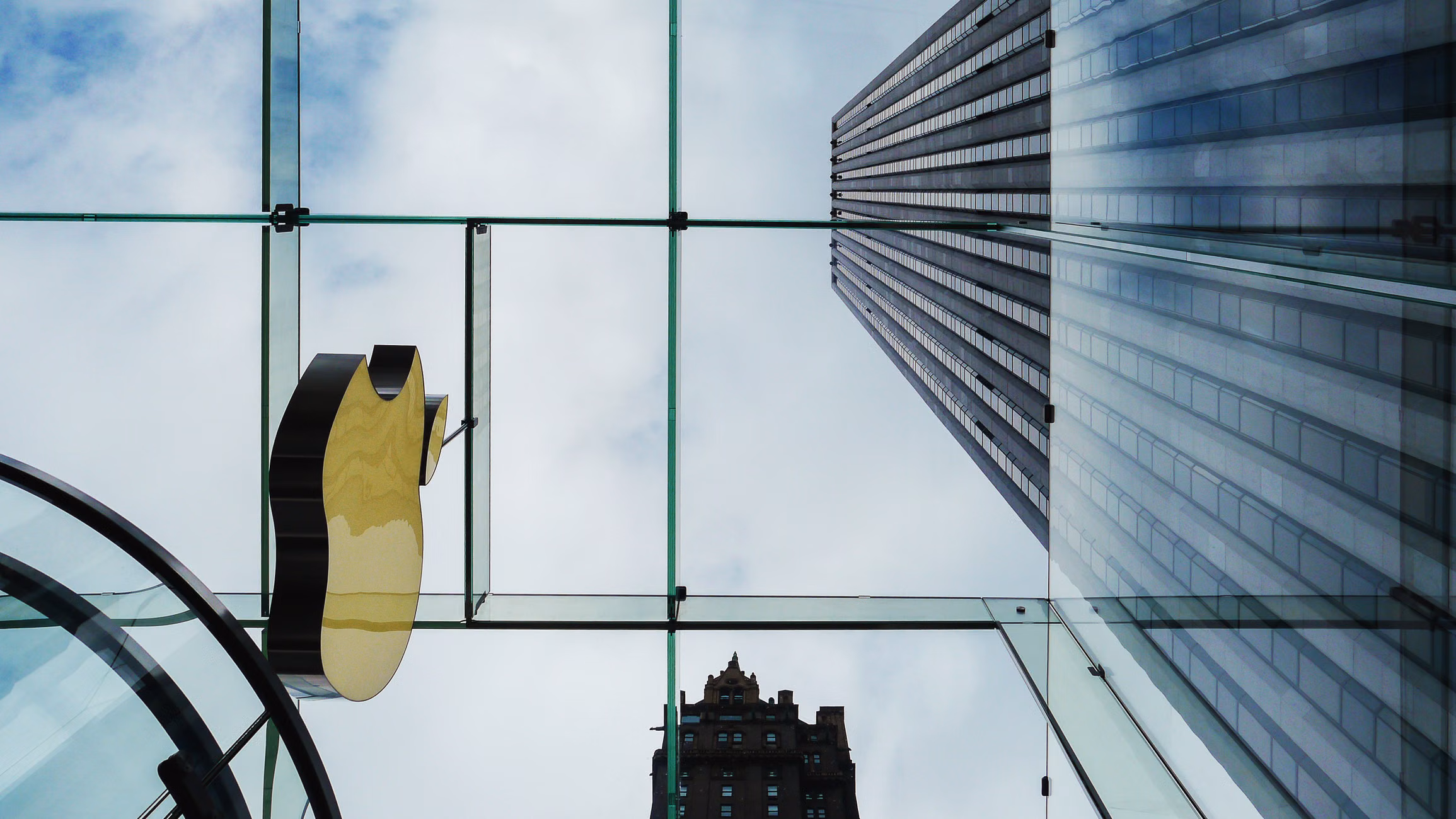 Looking up at skyscrapers through a glass ceiling, contrasting modern architecture.