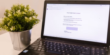 A close-up of a laptop screen showing a credit card security notification next to a potted plant.