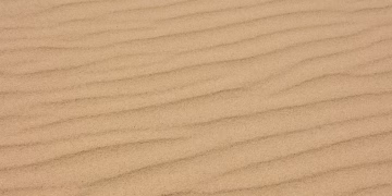 Textured close-up of rippled sand in a desert setting, ideal for backgrounds.
