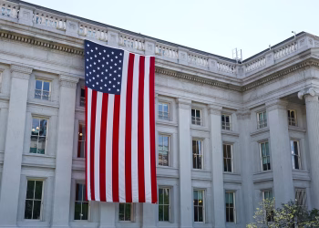 A large American flag hangs on a historic government building in Washington, D.C., showcasing national pride.