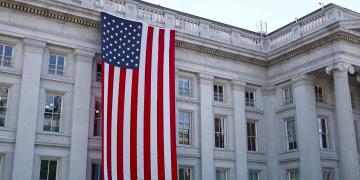 A large American flag hangs on a historic government building in Washington, D.C., showcasing national pride.