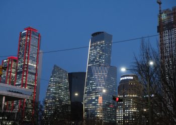 Modern skyscrapers illuminated at dusk against a dark sky.