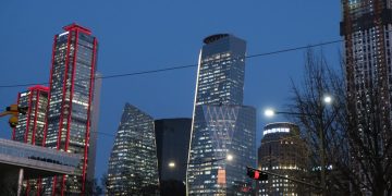 Modern skyscrapers illuminated at dusk against a dark sky.