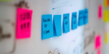 Sticky notes on a whiteboard during a creative brainstorming session in an office.