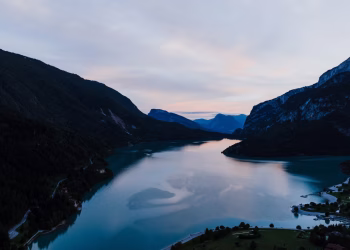 A breathtaking aerial view of Lake Molveno in Italy surrounded by mountains at twilight.