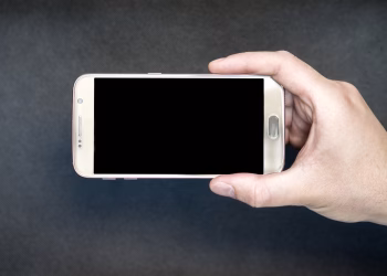 Close-up of a hand holding a smartphone with a blank screen, ready for design mockup.