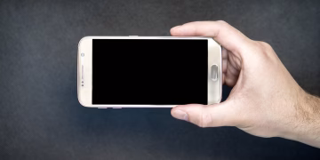 Close-up of a hand holding a smartphone with a blank screen, ready for design mockup.