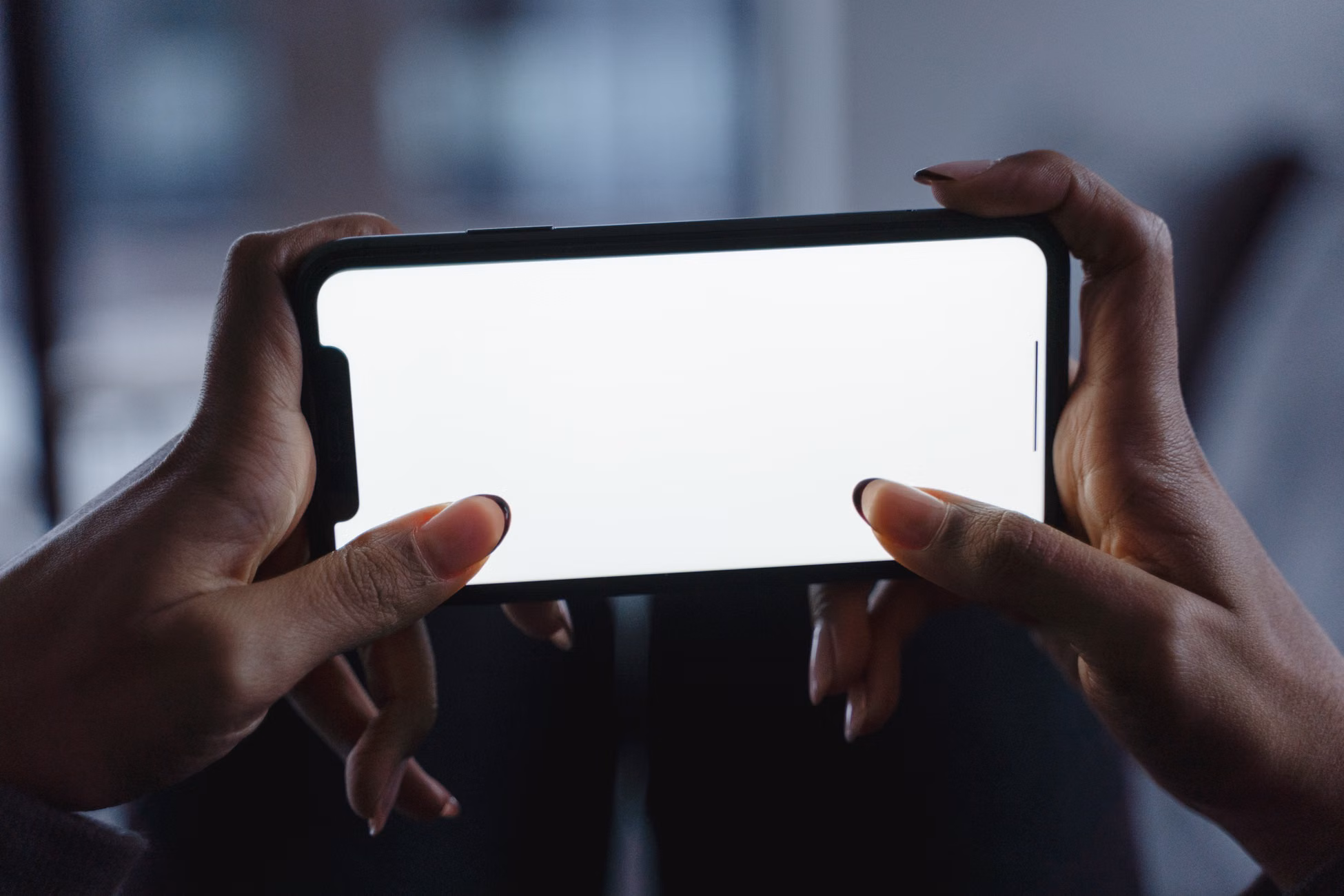 Close-up view of hands holding a smartphone with a blank white screen, perfect for mockup designs.