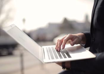 A business professional typing on a laptop in an outdoor setting, symbolizing remote work.