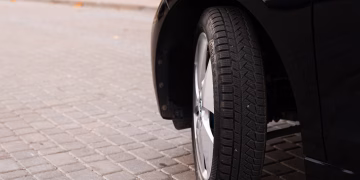 A black car's tire on a cobblestone road captures the essence of urban transportation.