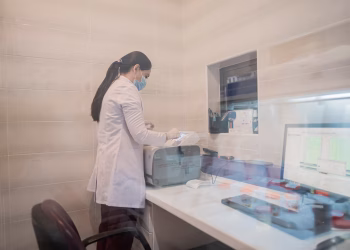 Woman in a lab coat examines equipment in a laboratory environment, Baku, Azerbaijan.