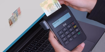Person using contactless device for ID payment verification on a laptop.
