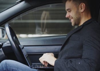 Man working on laptop inside a car
