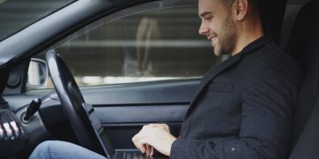 Man working on laptop inside a car