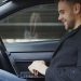 Man working on laptop inside a car