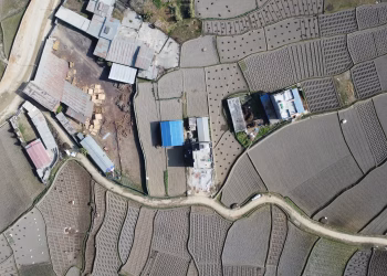 Aerial view of rural farmlands and buildings in Panauti, Nepal, showcasing agricultural patterns.