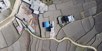 Aerial view of rural farmlands and buildings in Panauti, Nepal, showcasing agricultural patterns.