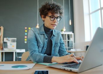 Woman working on a laptop in a modern office.