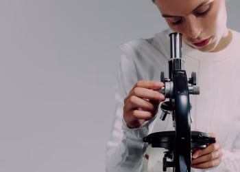A scientist carefully examining samples using a microscope in a modern laboratory setting.