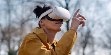A young adult using a virtual reality headset outdoors, experiencing immersive technology in a natural setting.