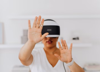 A woman interacts with virtual reality technology using a VR headset indoors.