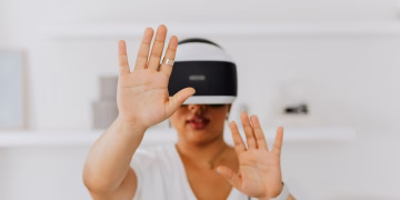 A woman interacts with virtual reality technology using a VR headset indoors.