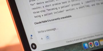 A laptop screen displays "claude fable 5 is currently unavailable."