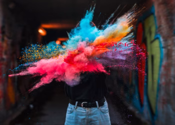 Vibrant powder explosion highlighting colorful creative expression with urban graffiti backdrop.