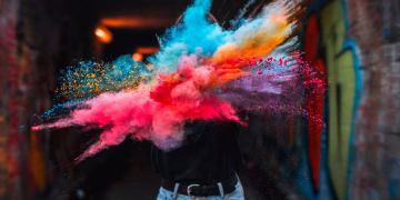 Vibrant powder explosion highlighting colorful creative expression with urban graffiti backdrop.