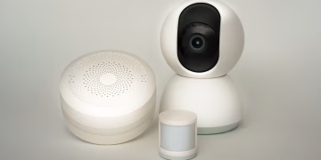 Modern smart home devices including a camera and sensors on a neutral background.
