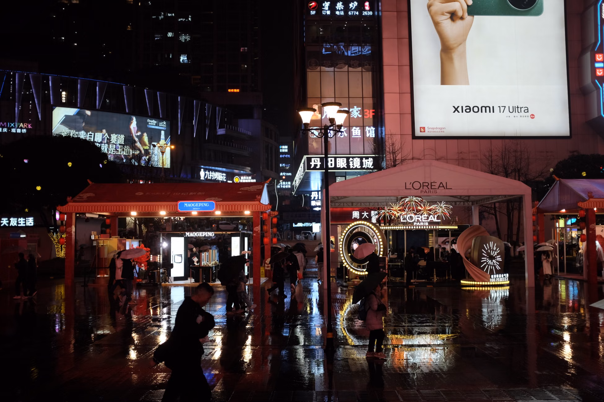 Lively night market scene in a bustling city with illuminated billboards and people.