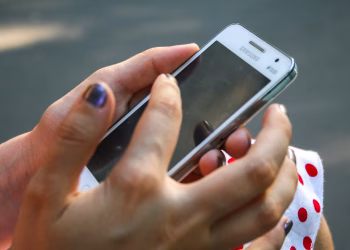 A woman interacts with a smartphone outdoors, focusing on connectivity and technology.