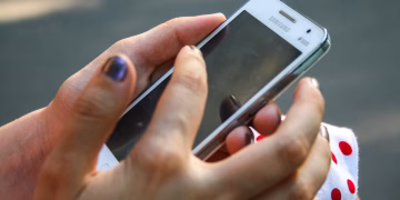 A woman interacts with a smartphone outdoors, focusing on connectivity and technology.
