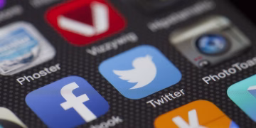 A detailed close-up of social media icons on a smartphone screen, including Facebook and Twitter.