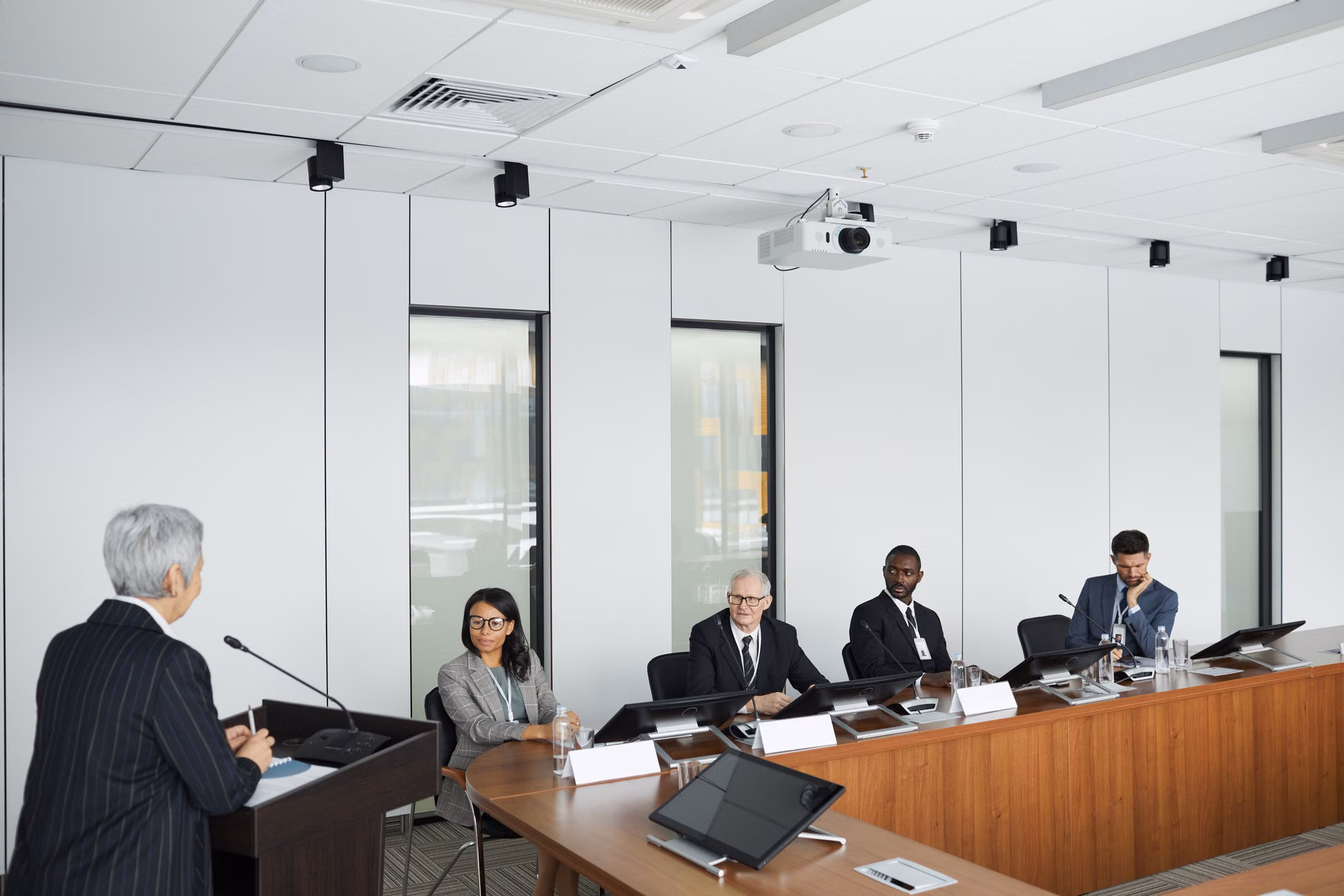 Business meeting with diverse panel and a speaker in a modern conference room.