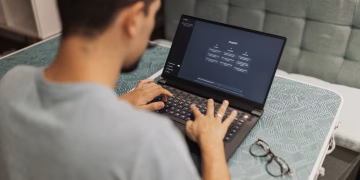A man working on a laptop displaying ChatGPT's interface in an indoor setting.
