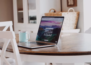 A sleek laptop on a wooden table with a mug, exemplifying a modern home workspace.