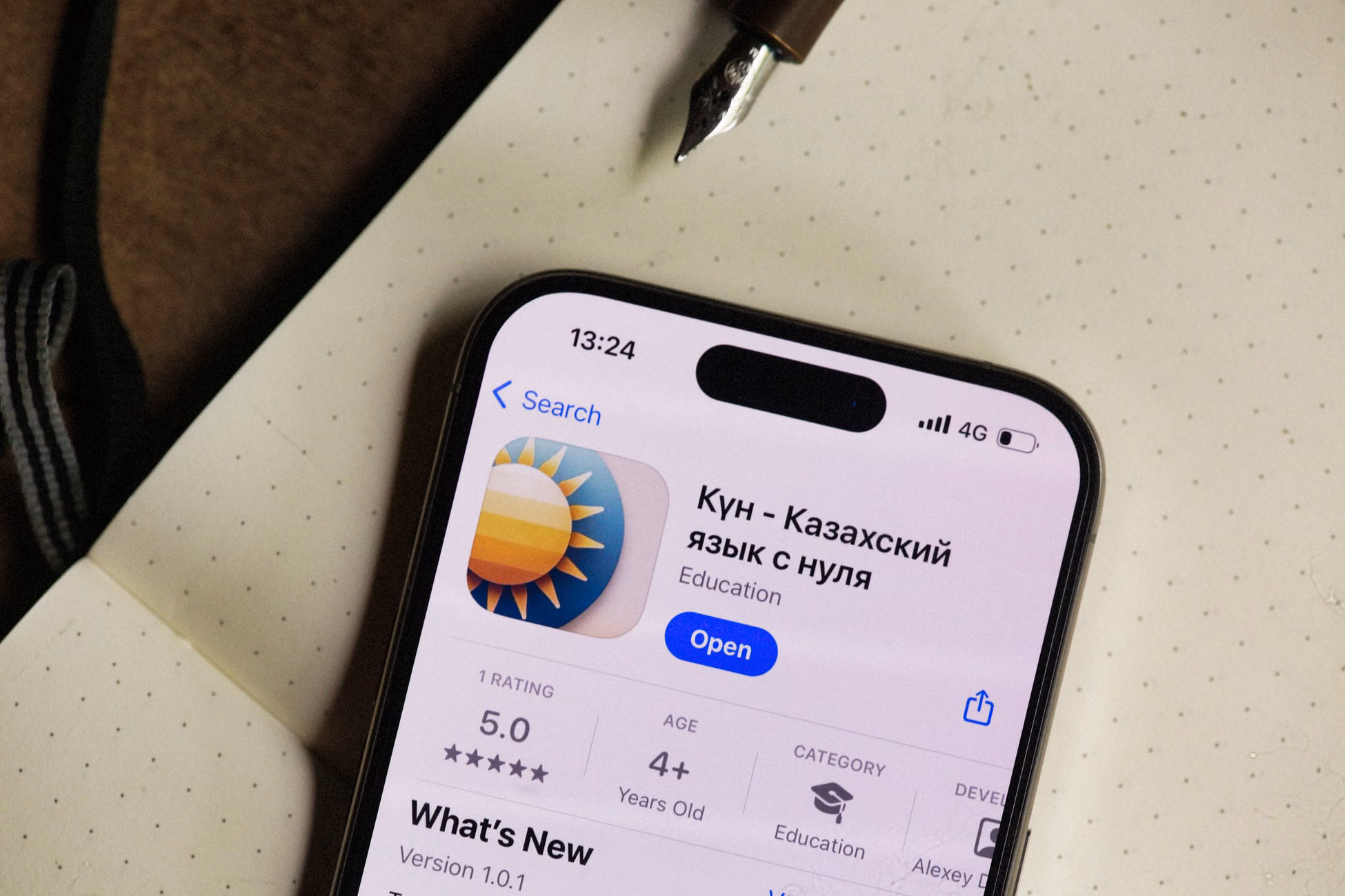 Close-up of a smartphone screen showing a Kazakh language learning app in an open notebook setting.
