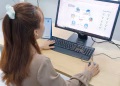 Young woman using desktop computer in office setting in Hanoi, Vietnam.