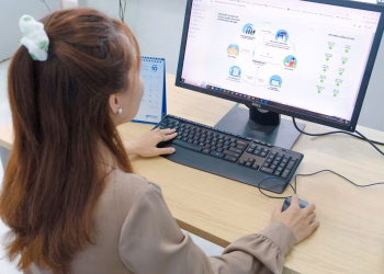 Young woman using desktop computer in office setting in Hanoi, Vietnam.