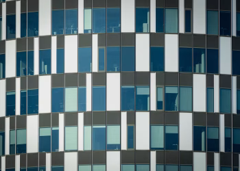 Close-up of a modern office building facade with geometric patterns and glass windows.